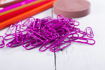 red, pink, purple color pencils and paper clips, ink pads on white wooden table background