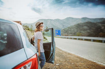 Travel - young beautiful hipster woman in hat travel by car, rent a car in vacations, image with...