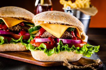 Tasty cheeseburgers with french fries served on fashionable black stone plate