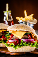 Tasty cheeseburgers with french fries served on fashionable black stone plate