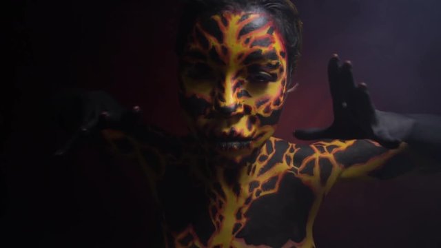 Body painting on the body of a girl in the form of volcanic lava, which dances demonic dance