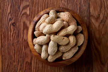 Unpeeled peanuts on a wooden background, top view, selective focus, shallow depth of field.