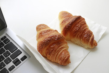 Croissant and laptop on the desk