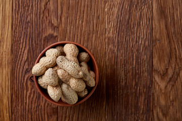 Unpeeled peanuts on a wooden background, top view, selective focus, shallow depth of field.