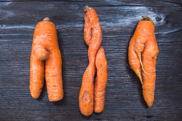 Funny forms of carrots on background of dark board