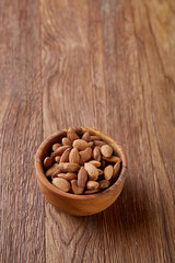 Tasty almond on a wooden plate over wooden background, top view, close-up, selective focus.
