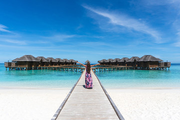 Woman with raised hands on bridge on beach in Maldives