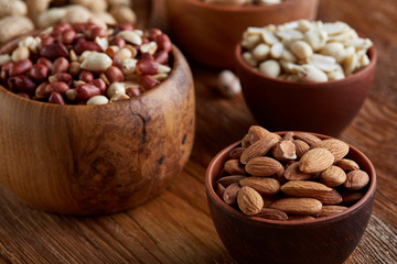 A composition from different varieties of nuts in a wooden bowls on rustic background, close-up, shallow depth of field