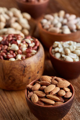 A composition from different varieties of nuts in a wooden bowls on rustic background, close-up, shallow depth of field