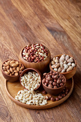 A composition from different varieties of nuts in a wooden bowls on rustic background, close-up, shallow depth of field