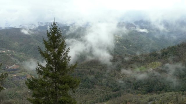 Early foggy morning in the Alps. Fog from the mountains falls into the valley. Perinaldo, Italy.