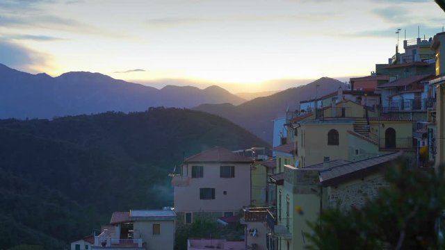 Early foggy morning in an alpine town. The rising sun illuminates the roofs of a medieval town in the mountains.. Perinaldo, Liguria, Italy.