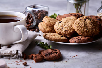 Fototapeta na wymiar Morning coffee in white cup, chocolate chips cookies on homespun napkin, close-up, selective focus