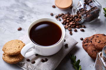 Morning coffee in white cup, chocolate chips cookies on homespun napkin, close-up, selective focus