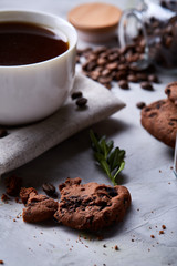 Morning coffee in white cup, chocolate chips cookies on homespun napkin, close-up, selective focus