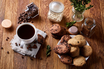 Morning coffee in white cup, chocolate chips cookies on homespun napkin, close-up, selective focus