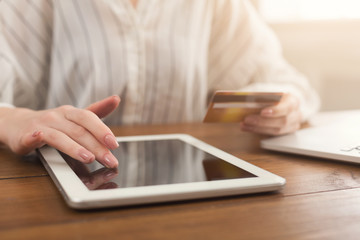Closeup of woman hands using tablet and holding credit card