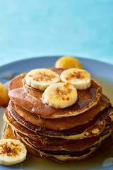 Pile of homemade pancakes with banana and walnuts on blue background, selective focus