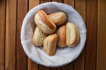 Basket of freshly baked dinner rolls with tableware in background. Macro