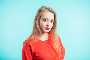 Beautiful young redhead woman . Pretty girl wearing red jacket looking at camera on blue light background