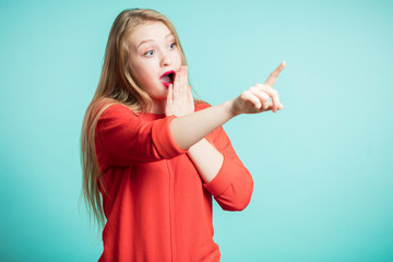 Woman happy and surprised shouts holds cheeks by hand. Beautiful girl pointing to looking right. Presenting your product. Expressive facial expressions