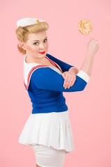 anime blonde girl with lollipop in hand up. we can do it styled girl with candy in hand. sea-woman styled blonde with lollipop on pink background isolated in studio