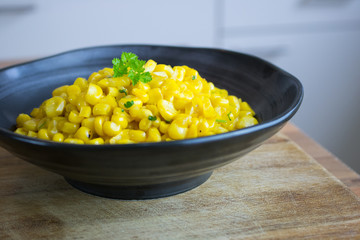 Food photography of a black bowl with cookeed yellow corn and a kitchen background