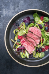 Traditional barbecue aged sliced fillet steak with lettuce and fruits as top view on a plate with copy space