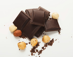 Broken dark chocolate bar and hazelnut isolated on white
