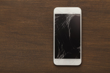 Broken smartphone on wooden table