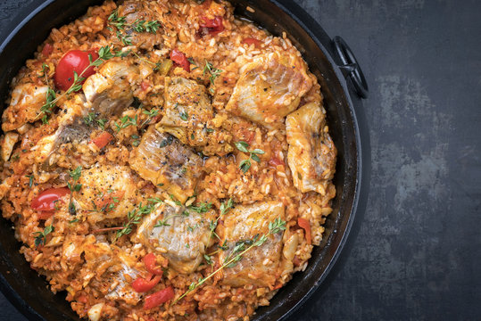 Traditional Louisiana fish jambalaya dish creole cajun with rice and tomatoes as top view in a pot with copy space right
