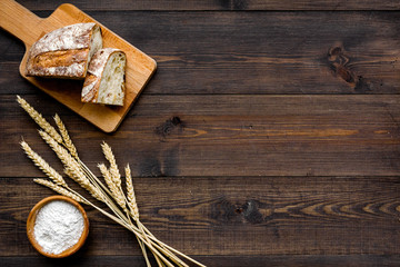 Homemade fresh bread sliced on cutting board on dark wooden background top view copy space