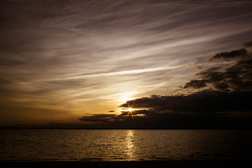 dramatic starbursts sunset over bay cloudy sky