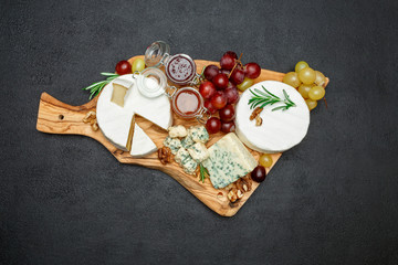 various types of cheese and jam on wooden cutting board