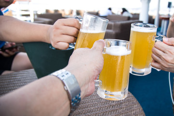 Three person knocking beer glasses  to toast in celebration