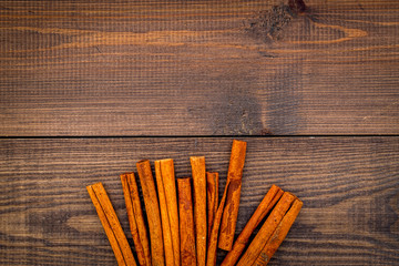 Cinnamon sticks on dark wooden background top view copy space. Condiment for mulled wine
