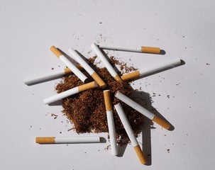 Heap of herbal smoking tobacco and cigarettes on white background