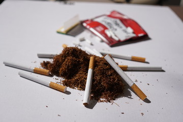 Heap of herbal smoking tobacco and cigarettes on white background