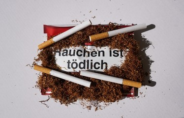 Tobacco addiction concept. Tobacco package warning messages Rauchen ist tödlich, German for...