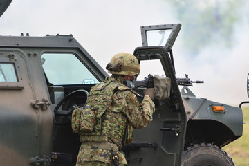 装甲車のドア越しに射撃する自衛官