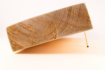 The end part of the wooden board, one edge of which is raised and held from falling by one thin match.