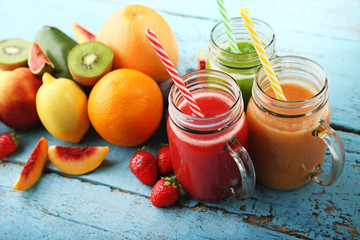 Sweet smoothie in glass jars with fruits on blue wooden table