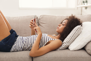 Young girl using mobile phone on sofa