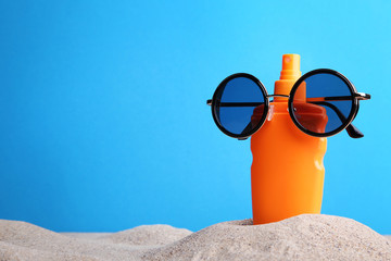 Sunscreen cream with sunglasses on beach sand