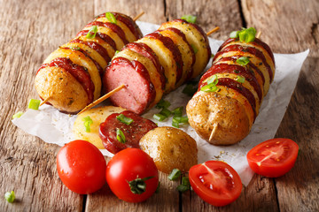 Freshly prepared shish kebab from potato skewers with sausage salami and tomatoes, green onions....