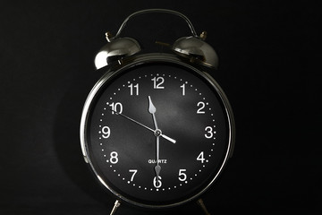 Old retro alarm clock with the hands set to 11:30 am or pm