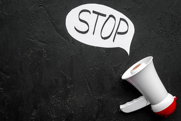 Demand to stop concept. Megaphone near cloud with word stop on black background top view space for...