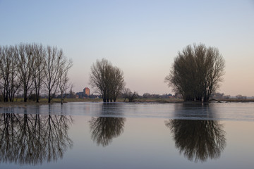 River in winter with church tower and small village in the background