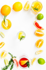Concept of alcoholic cocktail with fruits. Glass with beverage near oranges, grapefruit, lime and rosemary on white background top view pattern