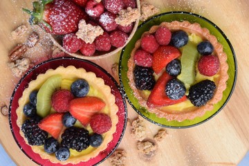 Two cake-baskets with cream and fresh berries. Small plate with strawberries, raspberries, blueberries, blackberries and some muesli